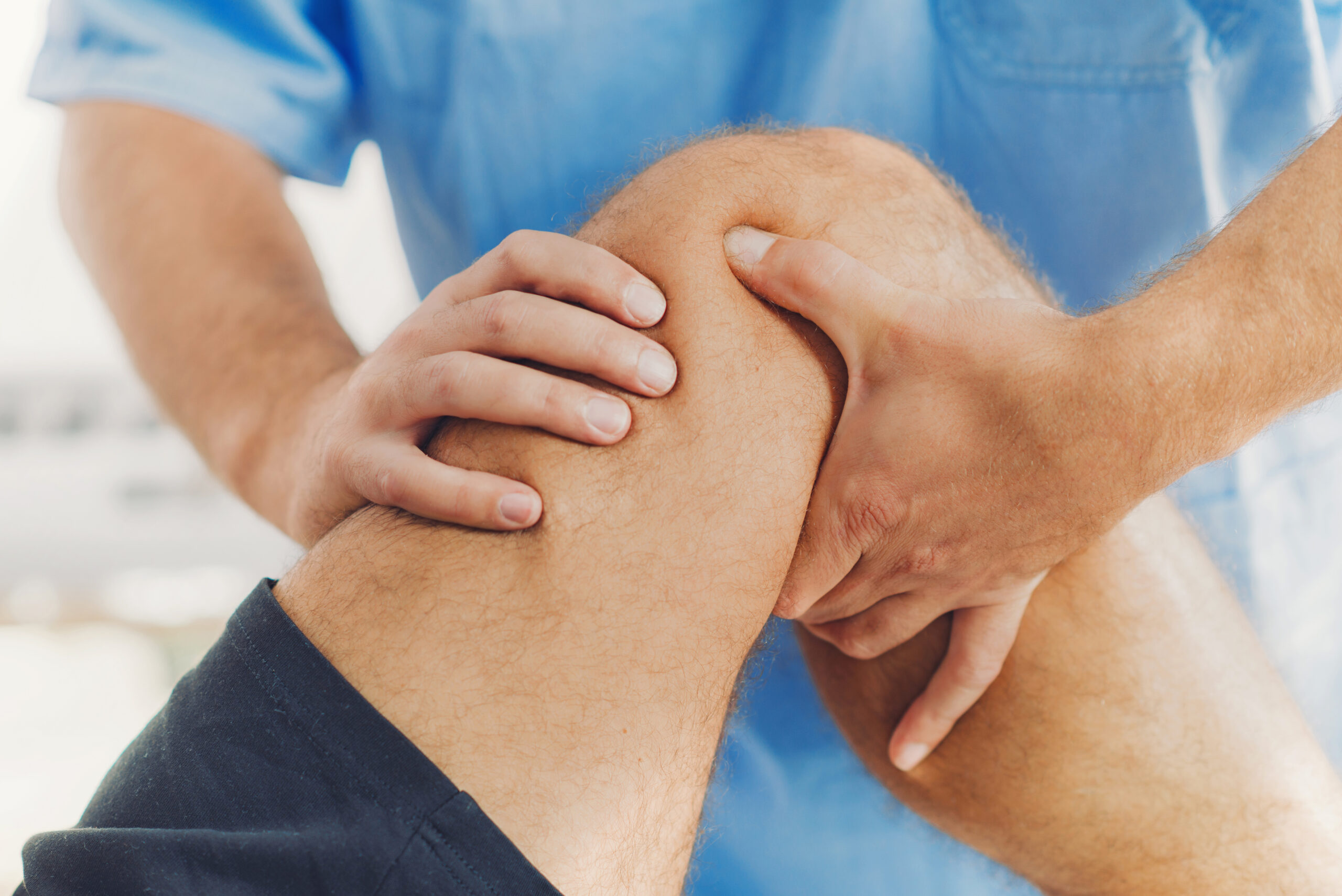A man's knee receiving physical therapy for acute knee pain treatment.
