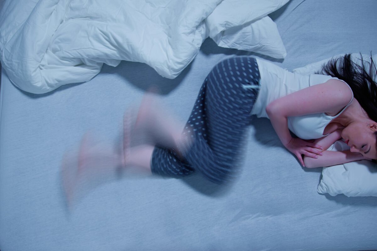 Restless leg syndrome causing a woman to kick and stir in her bed.