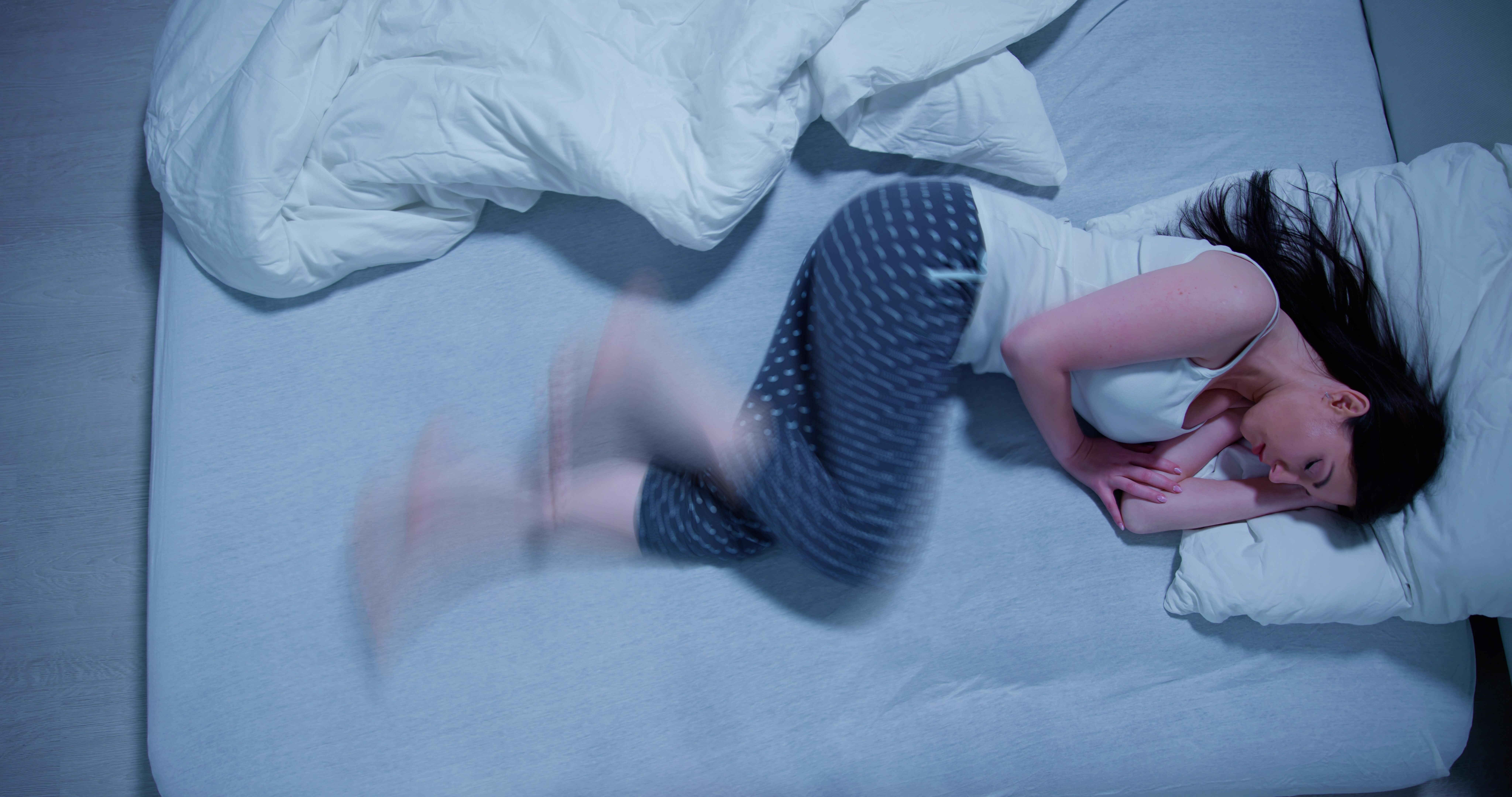 Restless leg syndrome causing a woman to kick and stir in her bed.