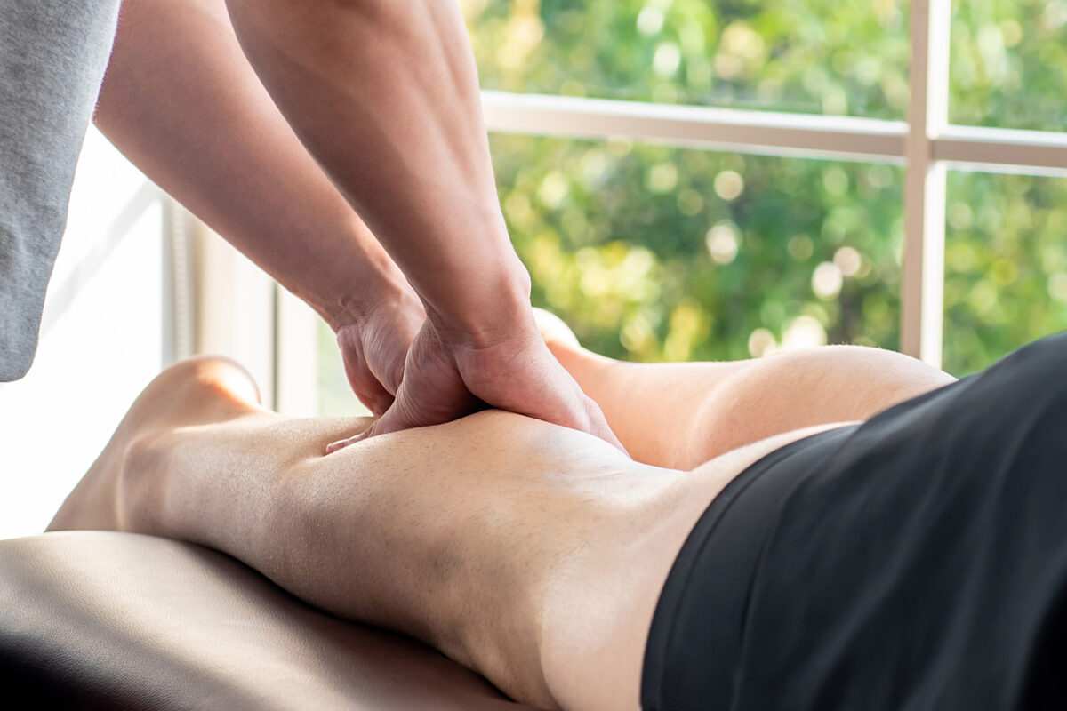 Treating severe muscle cramps, a man receives massage therapy on his calf.