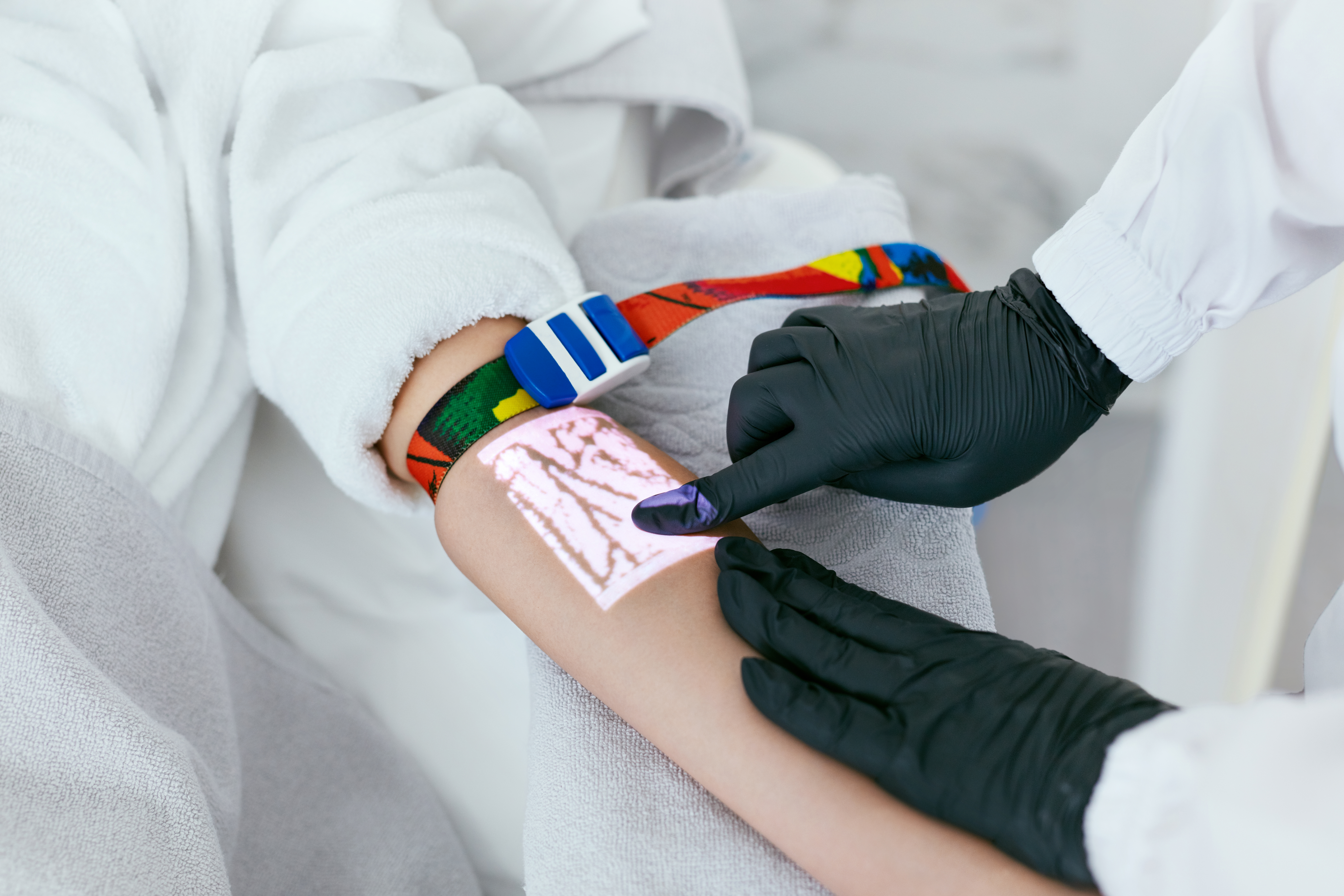 A doctor vein mapping a young woman's forearm as part of her treatment for poor circulation in hands and feet.