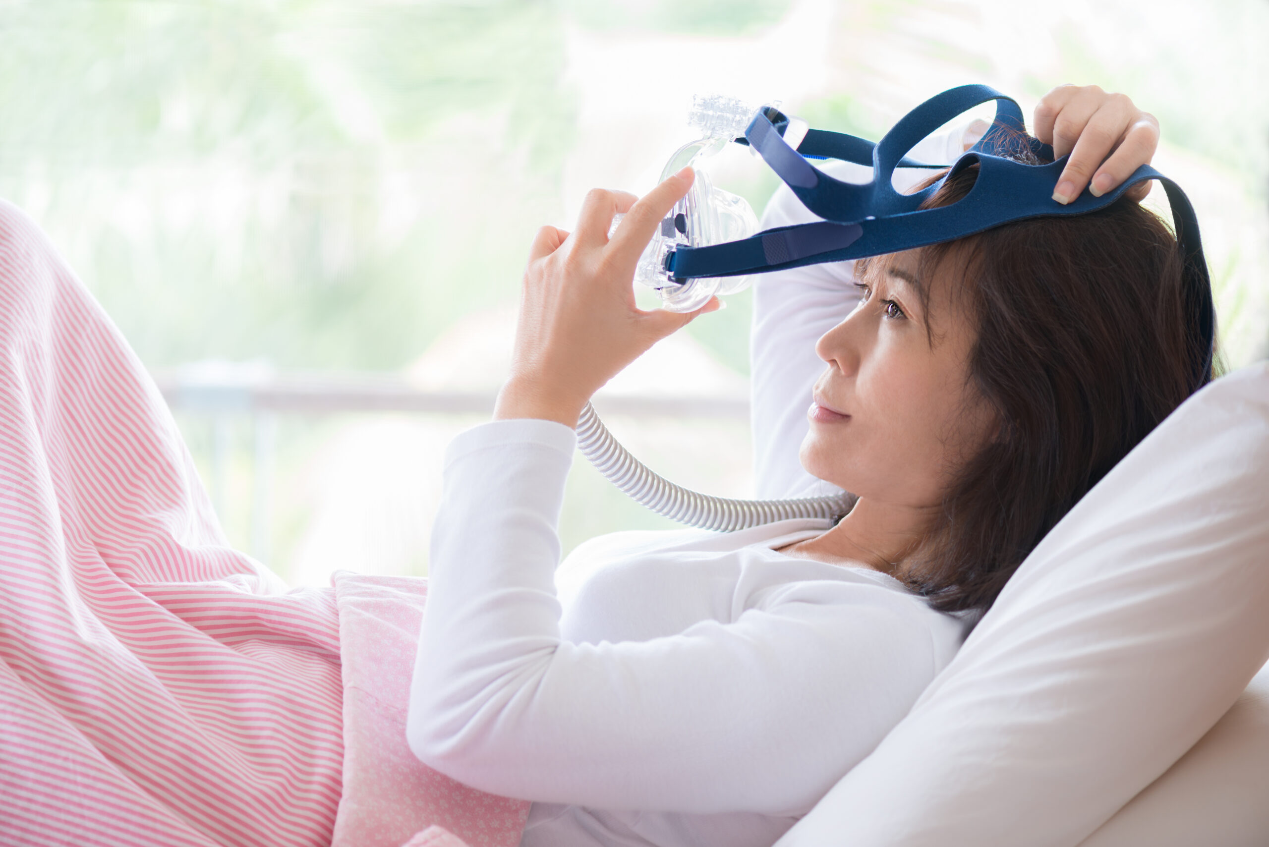 A woman getting ready for bed with the best CPAP therapy mask her doctor recommended to her.