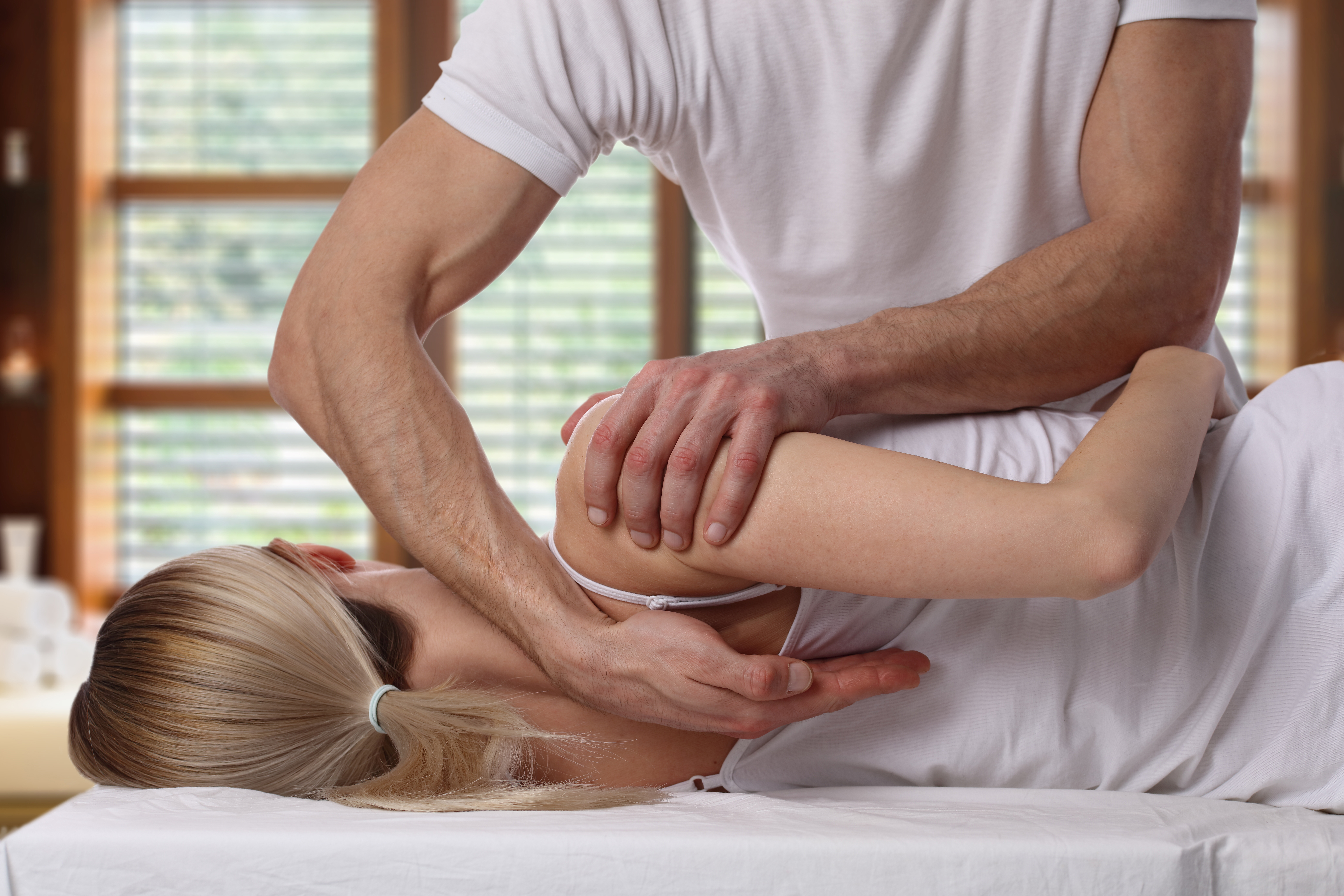 A woman lying on an adjustment table and receiving chiropractic care for back pain from a male chiropractor.