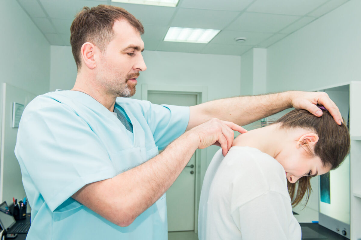 A male doctor inspecting a female patient's neck for possible neurological pain management strategies.