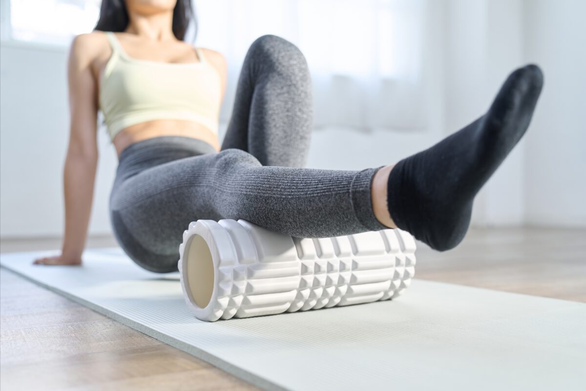 Muscle cramps in your legs can oftentimes be solved by sticking to a routine schedule of specific stretches, similar to this woman exercising on the floor.