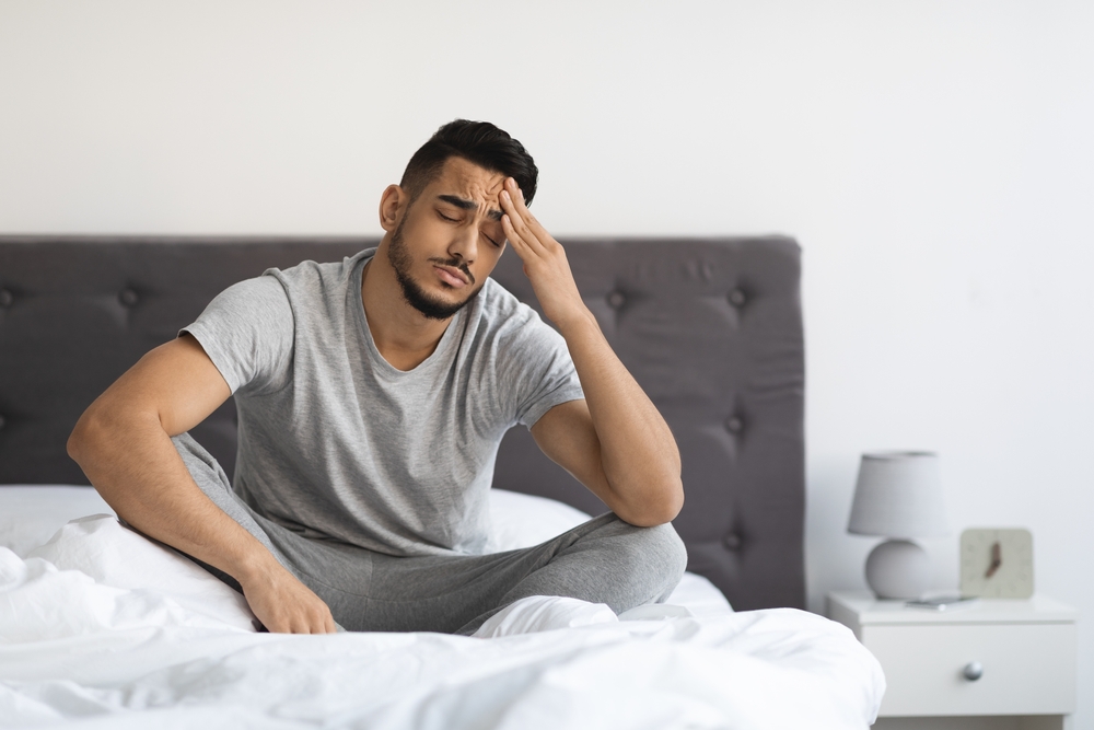 A man waking up without much sleep, thinking about sleep apnea mask alternatives.
