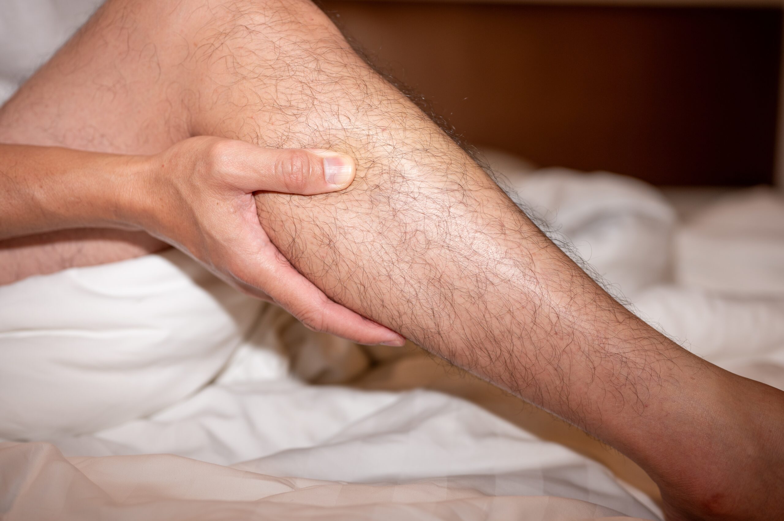 Leg muscle cramps, like the one shown on this middle-aged male in bed, don't have to make you suffer with the appropriate treatment.