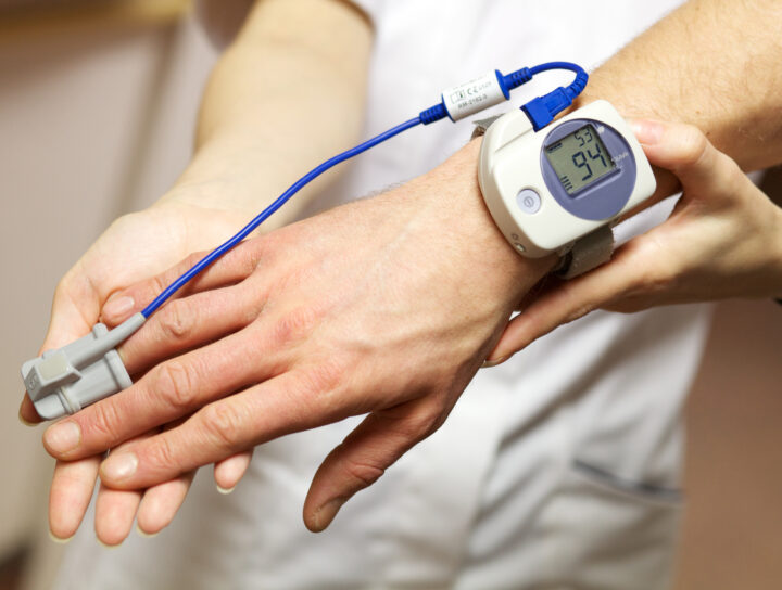 Personal stories behind sleep study at home tests reveal today's technological conveniences, as shown by this oxygen meter on an apnea patient's wrist and finger.