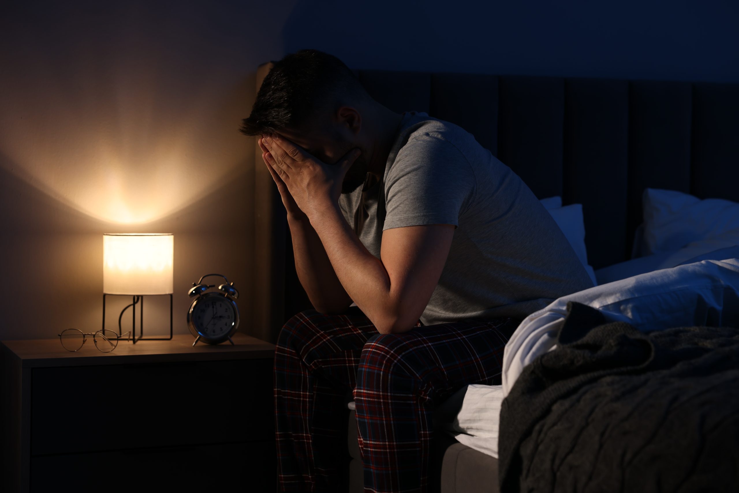 A sleepless man on the edge of his bed, considering CPAP alternatives.