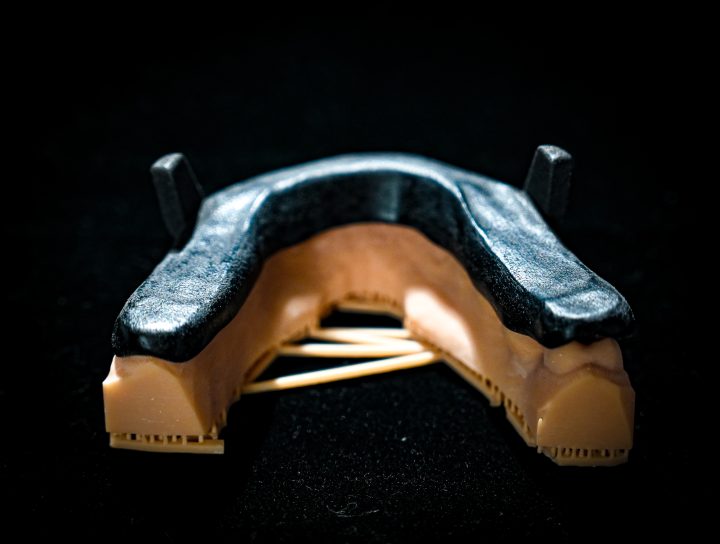 A brand new MAD sleep apnea device, or Mandibular Advancement Device, is casted in a spotlight with a black background.
