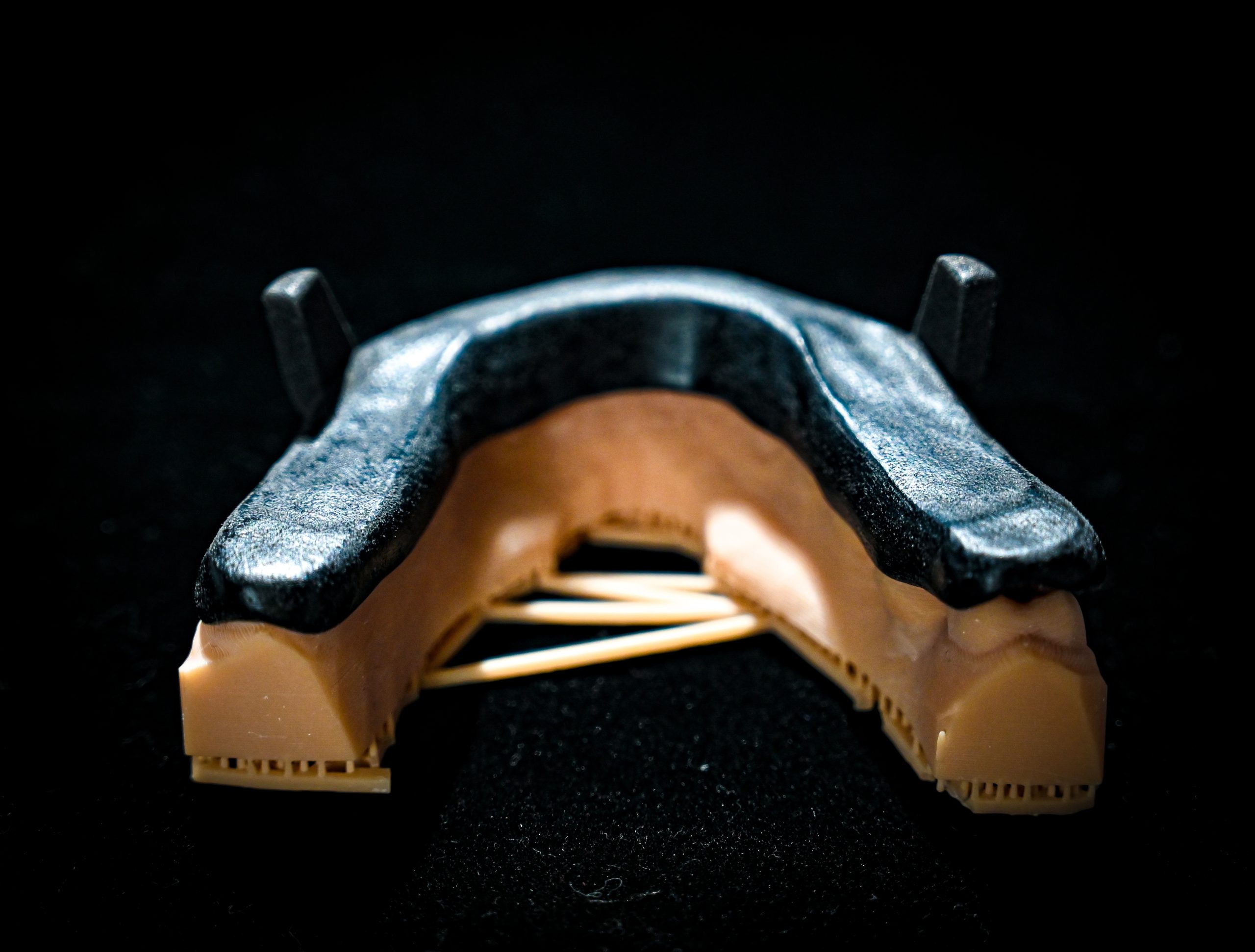 A brand new MAD sleep apnea device, or Mandibular Advancement Device, is casted in a spotlight with a black background.