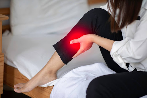 Leg cramps at night, which this young female adult is experiencing as she gets ready for bed in her room, are painful but have several remedies.