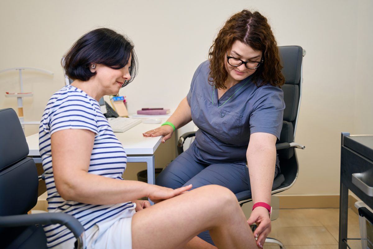 A middle-age woman with varicose veins receives care from a pain management specialist and doctor at her trusted vein clinic.