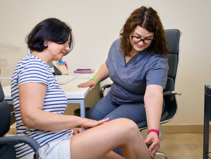 A middle-age woman with varicose veins receives care from a pain management specialist and doctor at her trusted vein clinic.