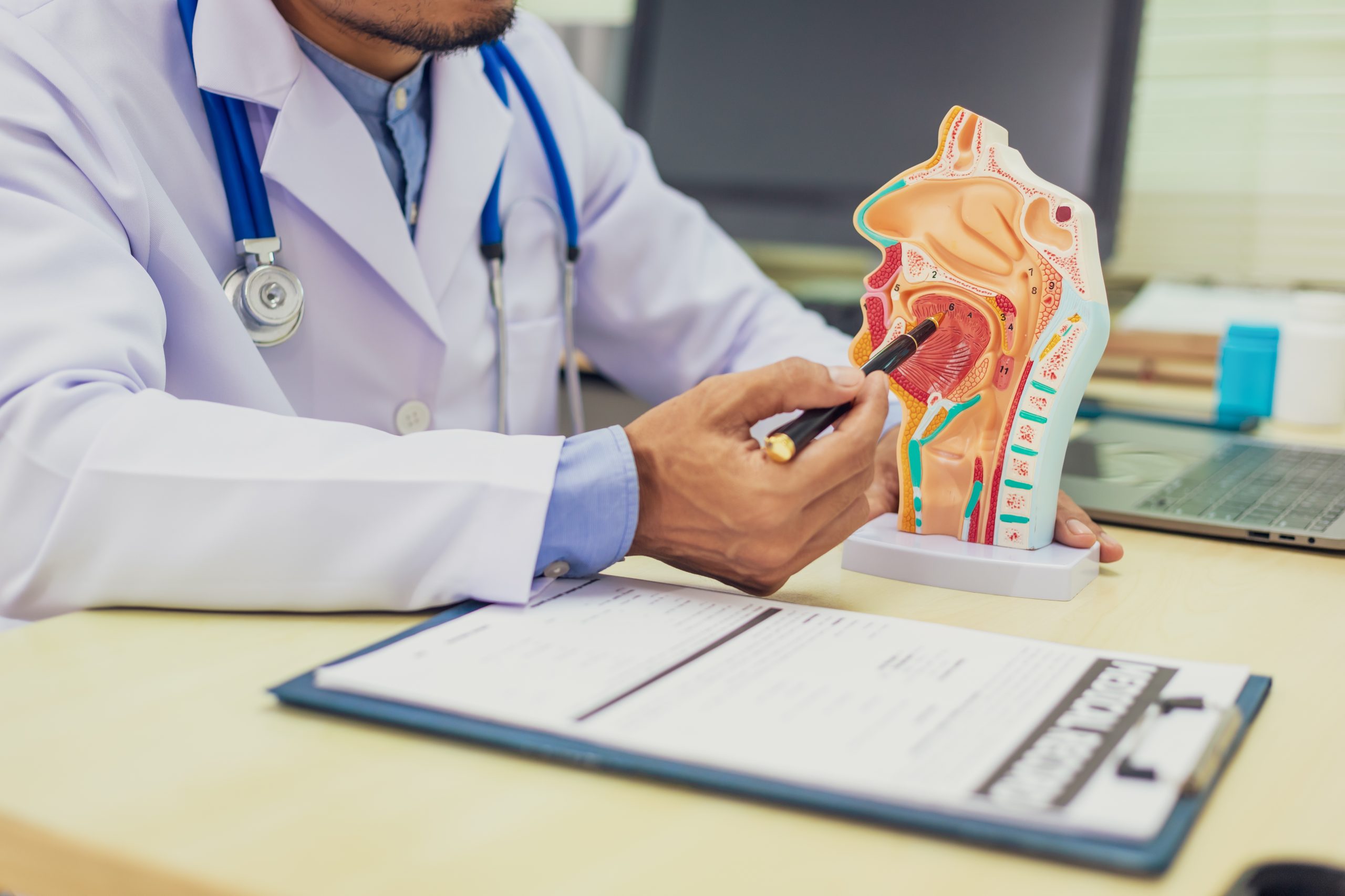 A doctor explaining OSA treatment with a diagram tool on his desk with a pen and clipboard.