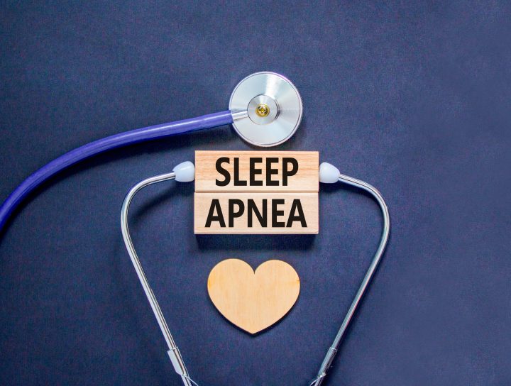 A doctor's stethoscope sitting near a heart illustration on a dark background, visually illustrating sleep apnea test kit treatment.