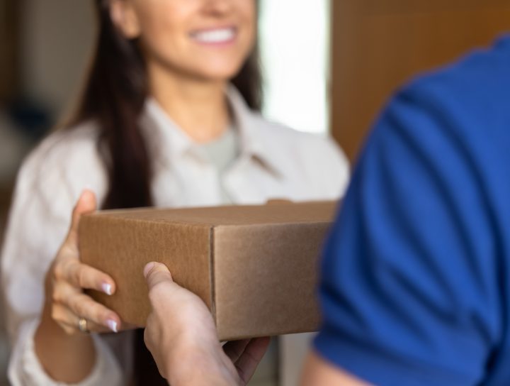 A smiling woman delivering a mail order sleep test to a man at his home.