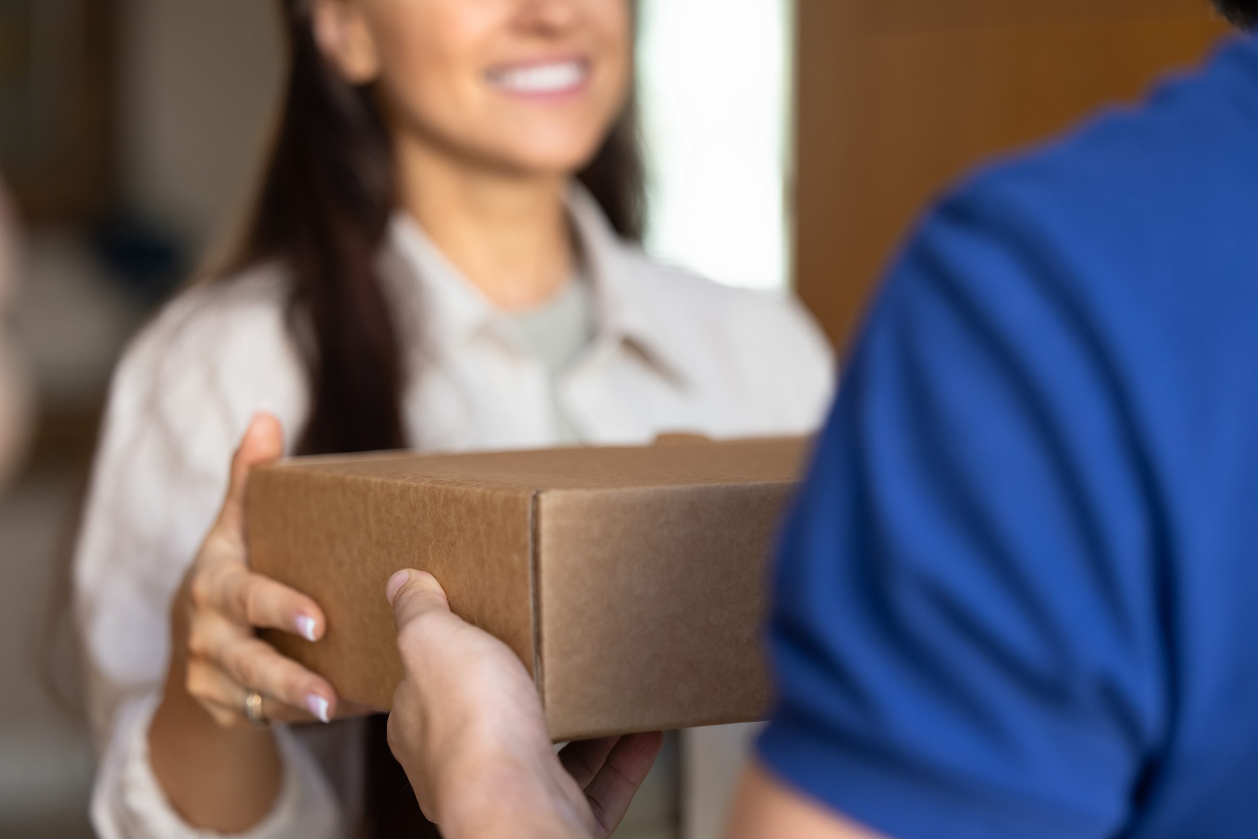 A smiling woman delivering a mail order sleep test to a man at his home.