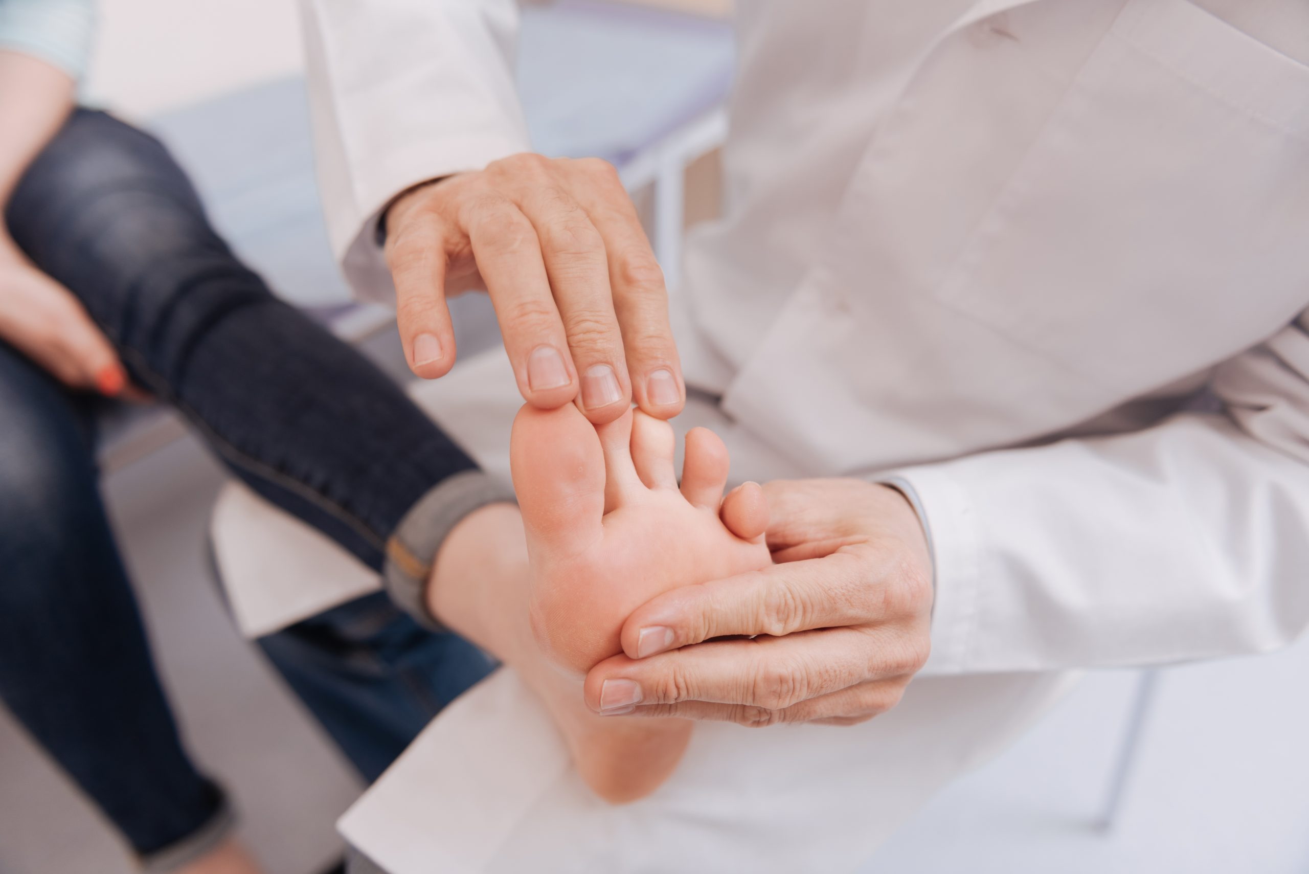 A young woman has her toes inspected by a pain management specialist for treatment for neuropathy in legs and feet.