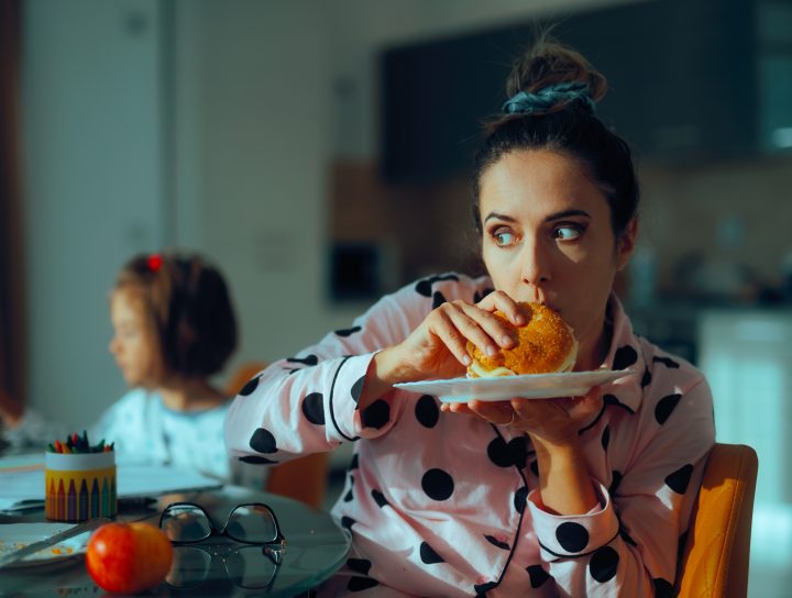 Processed foods, similar to the cheeseburger this lady is eating in her kitchen, can create more leg circulation issues.