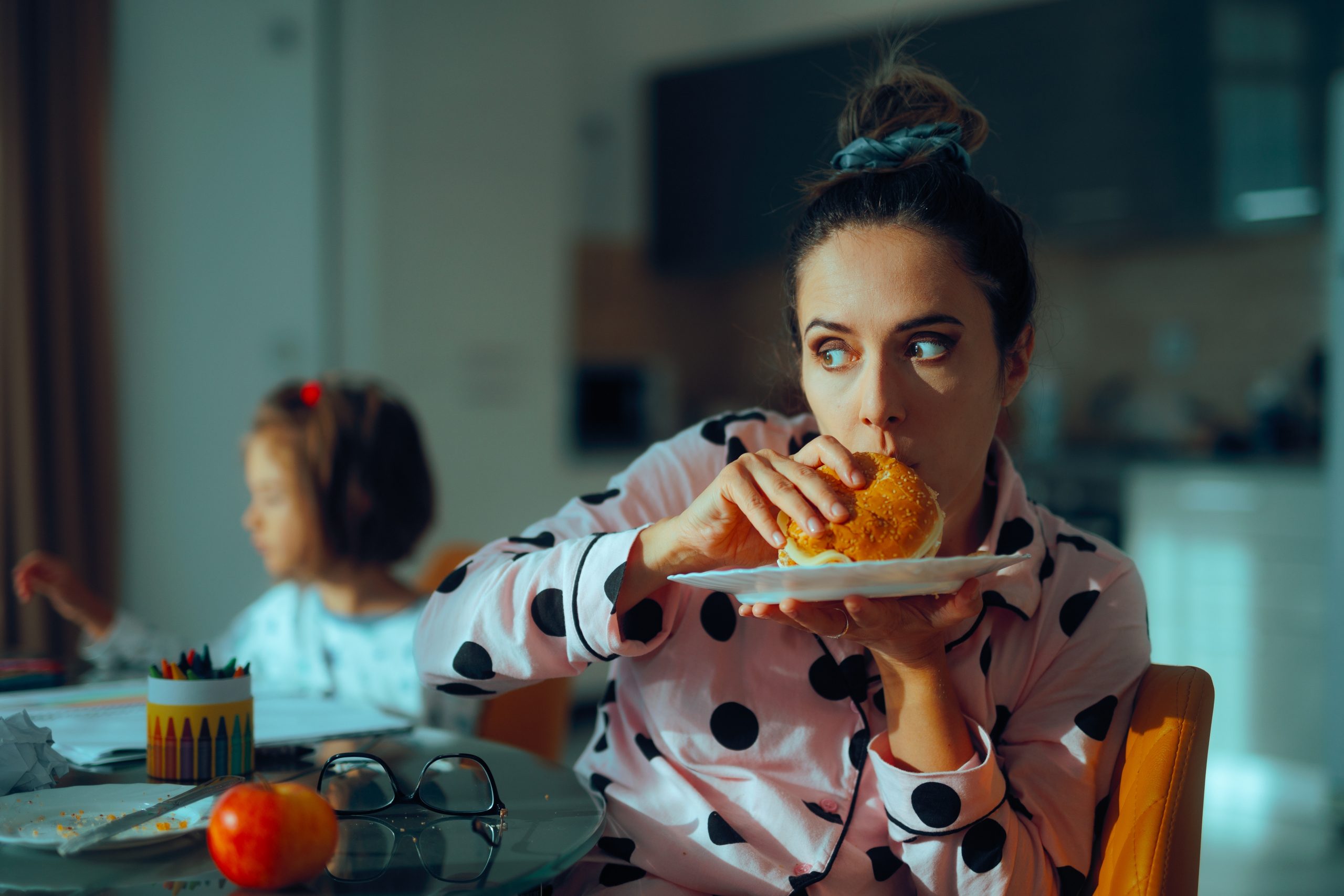 Processed foods, similar to the cheeseburger this lady is eating in her kitchen, can create more leg circulation issues.