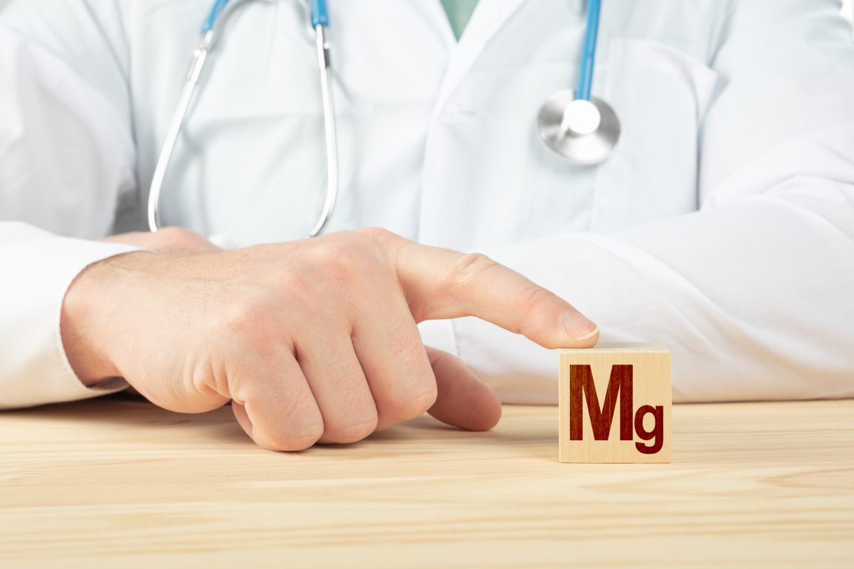 A doctor's hand pointing to "Mg," the chemical abbreviation for Magnesium, which helps with leg muscle cramps.