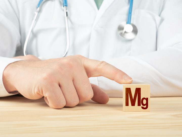 A doctor's hand pointing to "Mg," the chemical abbreviation for Magnesium, which helps with leg muscle cramps.