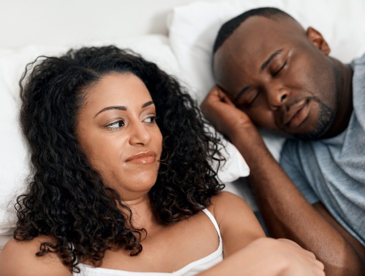 A wife looking at her husband in bed who is dealing with sleep apnea, considering treatment for sleep apnea.