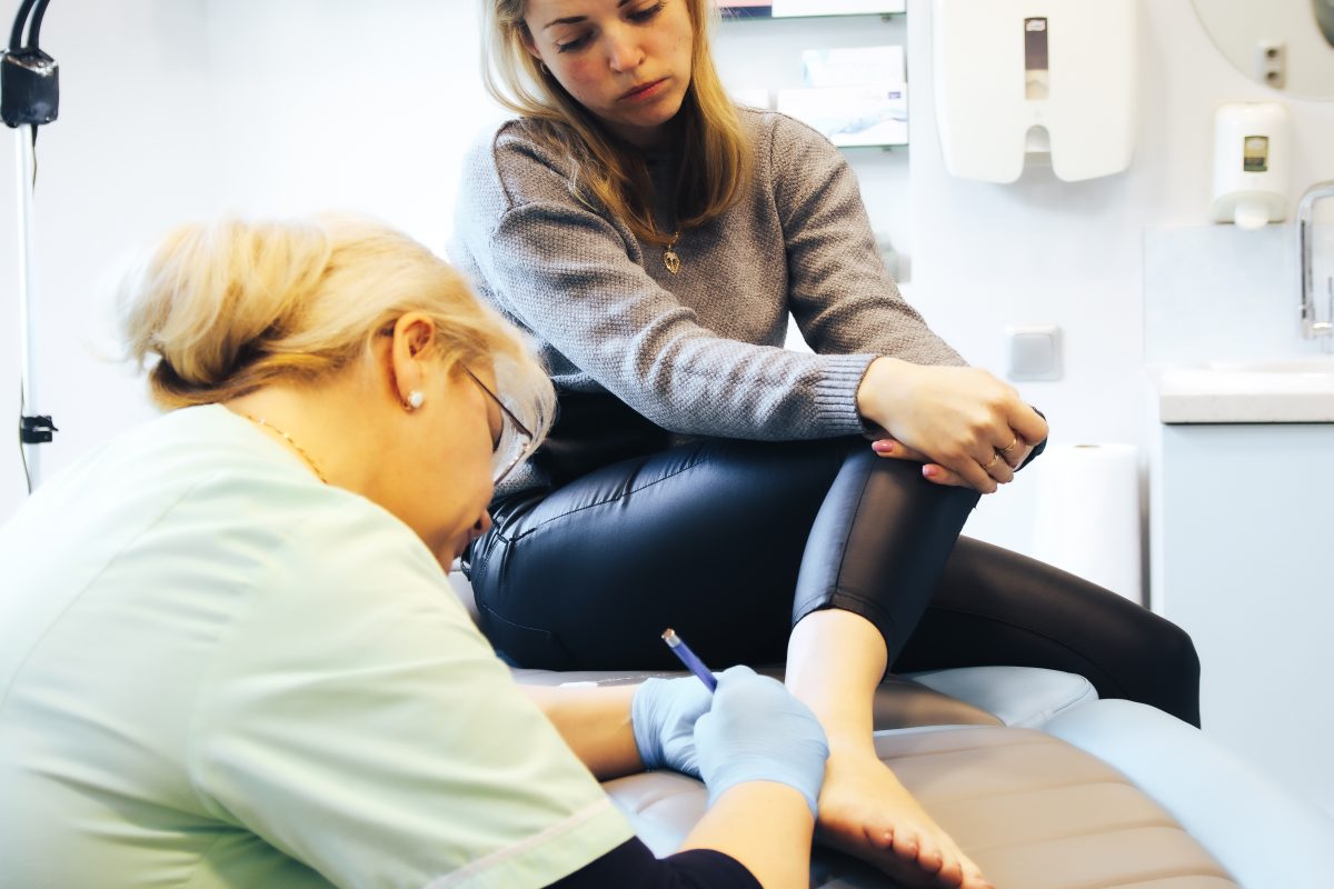 A female patient considering sclerotherapy for healthy veins as she gets checked by a pain management vein specialist in a doctor's room.