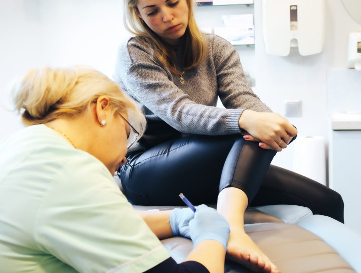 A female patient considering sclerotherapy for healthy veins as she gets checked by a pain management vein specialist in a doctor's room.