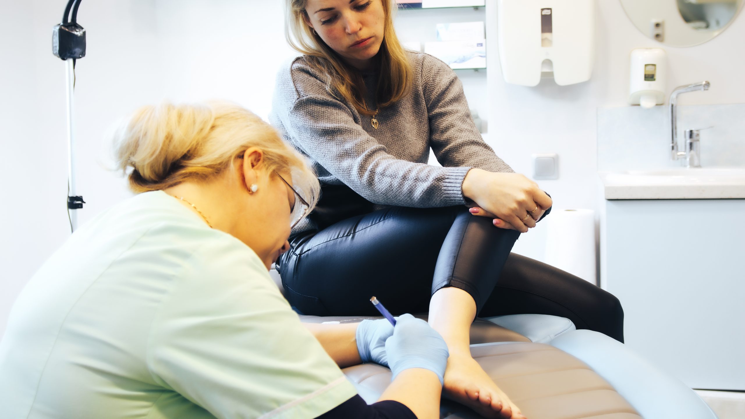 A female patient considering sclerotherapy for healthy veins as she gets checked by a pain management vein specialist in a doctor's room.