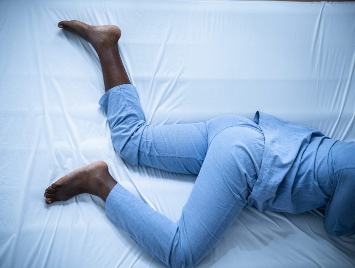 A body in a bed at night, with the individual struggling through restless leg syndrome.
